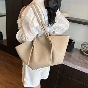 Chic beige pebbled leather tote bag with unique knotted strap for stylish daily commuting