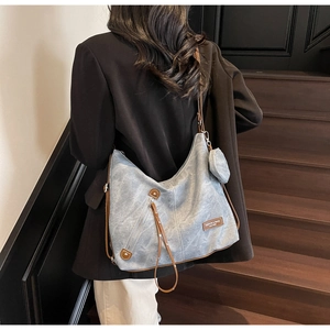 Detail of gray canvas tote bag with side zipper and small coin purse on a wooden staircase