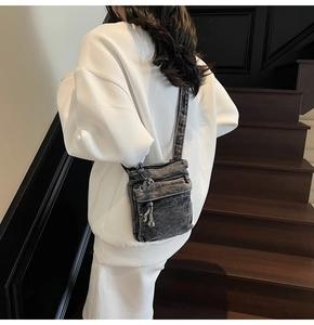 Dettaglio della borsa a tracolla in denim grigio lavato con tasche a zip e stile vintage