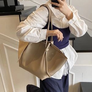 Large beige leather tote bag with stylish long knot strap shown on a model for daily commute