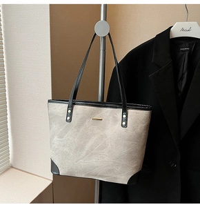Detail of trendy tote bag featuring suede texture with leather trim and gold metal accent
