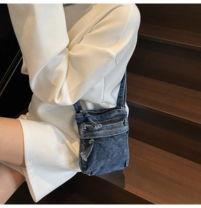 Dettaglio di borsa a tracolla in denim blu vintage con cerniere multiple e bordi