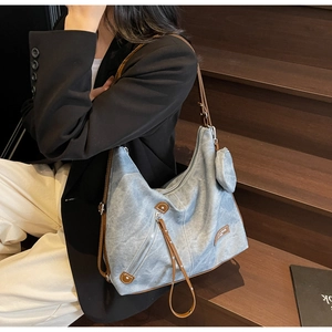 Detail of blue tote bag with brown leather trim and round coin purse on wood stairs