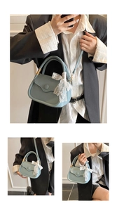 Close-up of light blue leather tote bag with lace bow handle and gold hardware detail
