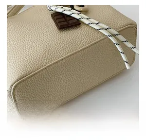 Vue détaillée du sac beige montrant les coutures précises et la texture du cuir
