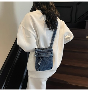 Dettaglio posteriore di una borsa a tracolla in denim blu con doppia cerniera lampo