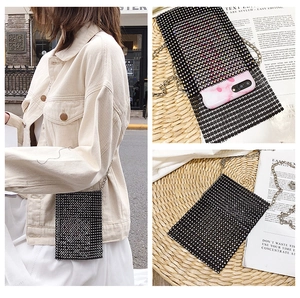 Vista dettagliata della borsa porta cellulare nera con strass e catena in metallo su modella