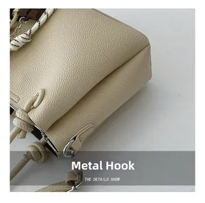 Détail des crochets en métal argenté et texture grainée d'un sac seau beige