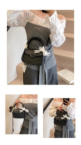 Detail of black pebbled leather handbag featuring a white lace bow and adjustable strap