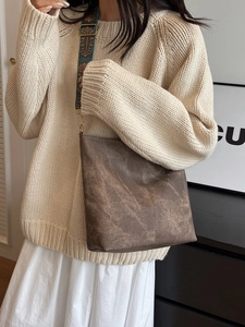 Brown textured tote bag with ethnic style strap shown on a model in knitwear