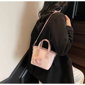 Pink mini tote bag detail showing cute dog charm and adjustable leather shoulder strap
