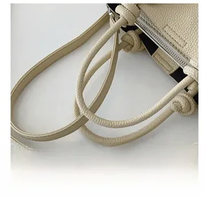 Vue détaillée du sac en cuir beige avec bandoulière nouée et fermeture éclair en métal
