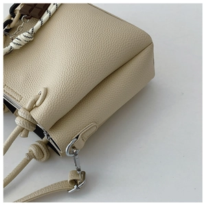 Vue détaillée du sac seau en cuir crème avec fermeture éclair et attaches métalliques