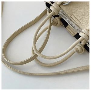 Détail de la poignée en cuir grainé blanc crème avec nœud et détails zippés argentés