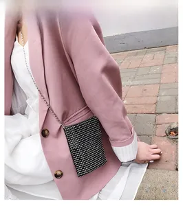 Dettaglio della mini borsa porta cellulare nera con strass e catena in metallo argentato su modella
