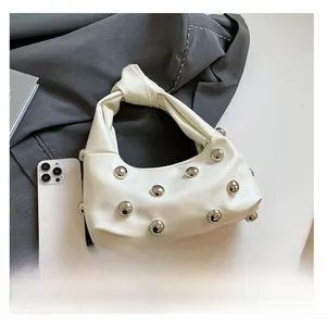 Detailed view of a white leather underarm bag with silver studs and knot handle design
