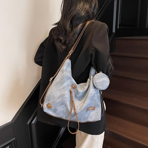 Retro light blue canvas tote bag with brown leather trim carried by a model on stairs