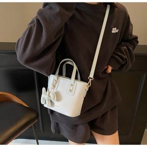 Light blue bucket bag featuring dual handles, a shoulder strap, and a white decorative charm