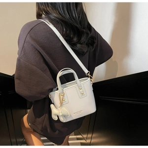 Light blue bucket bag with gold rivets and rabbit charm worn by a model on stairs