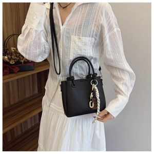 Détail du sac cabas en cuir noir avec poignée en corde tressée et décoration de chaîne