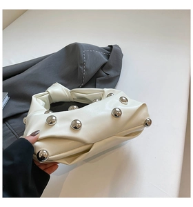 Detail of cream white leather bag with large silver studs and knotted handle design