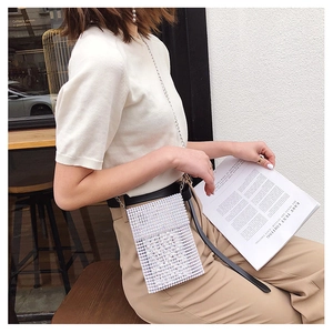 Dettaglio elegante borsa a tracolla in perle fatta a mano con sottile catena indossata da modella