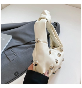 Detail of white PU leather hobo bag with silver studs and iconic knotted top handle