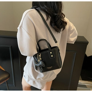 Detail view of black leather bucket bag with gold lettering and cute dog charm attachment