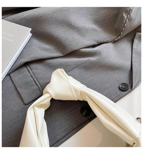 Detail of a white leather knotted handle on a shoulder bag with soft matte texture