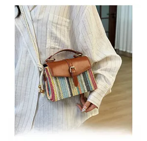 Detail of multi-color woven straw bag with brown leather flap and golden buckle closure