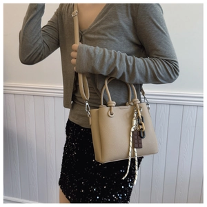 Détail du sac seau en cuir grainé kaki avec poignée nouée et breloque décorative