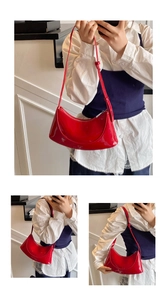 Detail of red patent leather crescent bag with adjustable strap and silver metal zipper