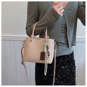 Vue détaillée du sac seau rose avec grain litchi et pendentif chocolat décoratif