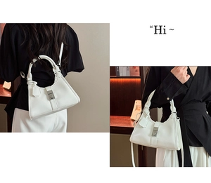 Detail view of a white pleated dumpling bag with silver clasp and round handle strap