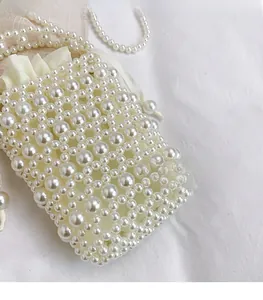 Detailed view of handmade white pearl woven bucket bag with satin drawstring liner
