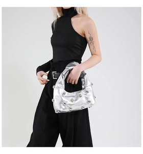 Close-up of metallic silver underarm bag with decorative studs and knotted handle detail