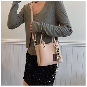 Détail du sac seau en cuir grainé rose avec poignée nouée et bandoulière réglable