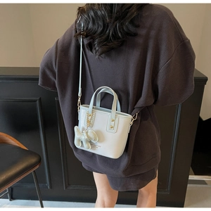 Detail of grey bucket bag with adjustable strap and small elephant charm accessory