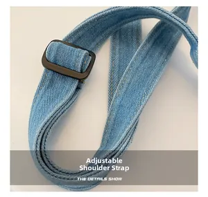 Détail de la bandoulière réglable en denim avec boucle noir mat sur un sac bleu clair
