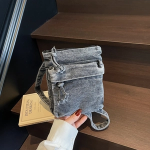 Borsa a tracolla vintage in denim grigio con frange su una scala di legno rustica
