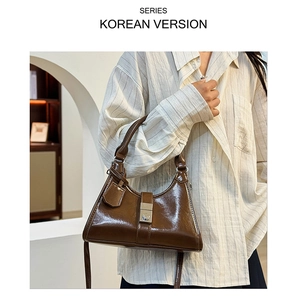 Close-up of brown glossy faux leather shoulder bag with metallic clasp and vintage handle