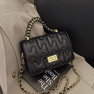 Borsa a tracolla in pelle trapuntata nera con catena dorata su sfondo alla moda