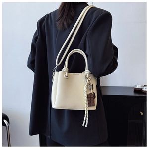 Détail du sac seau crème minimaliste avec breloque chocolat et poignée nouée sur modèle