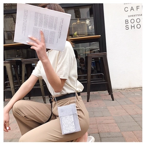 Mini borsa per cellulare in perline bianche con catena d'argento indossata in stile street