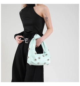 Detail of light mint green patent leather shoulder bag with silver studs and knot handle