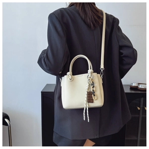 Sac seau en cuir crème grainé avec charms décoratifs en chocolat et bandoulière élégante