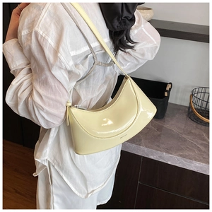 Detail of light yellow glossy patent leather crescent bag with NO FILTER text print