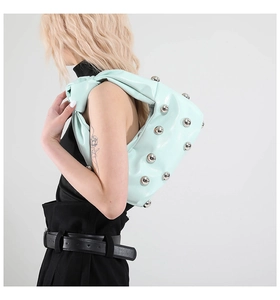 Detail of mint green shoulder bag featuring silver rivets and stylish knotted strap