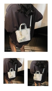 Detail of light blue mini tote bag with dog charm and gold hardware on textured PU leather