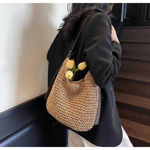 Close-up of woven straw hobo bag with dark brown leather strap for beach vacations